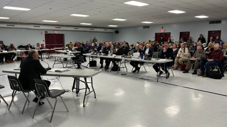 A room filled with people listen to arguments on a potential project proposed by a Calgary-based company.