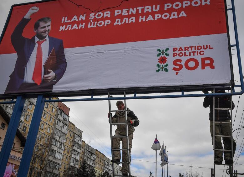 Workers put up an election billboard.