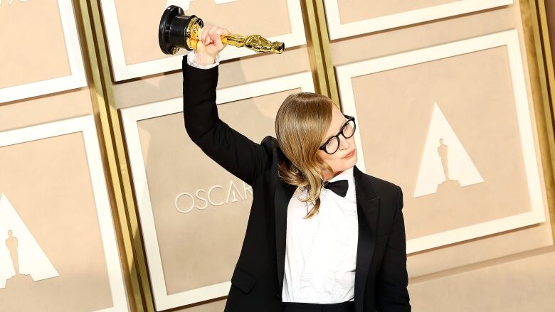 A woman raises an award over her head.