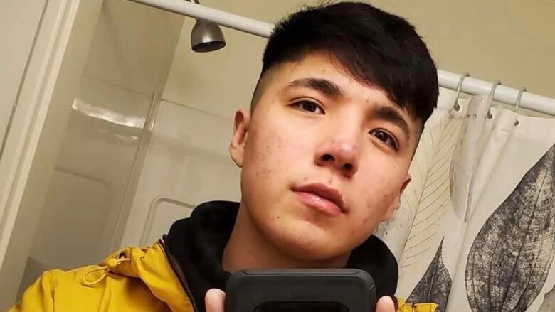 A young Indigenous man is pictured taking a bathroom mirror selfie.