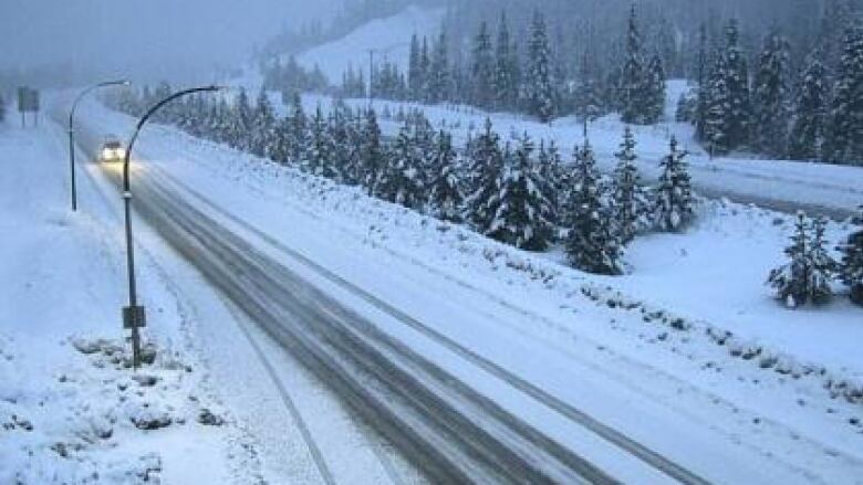 A snowy highway is pictured in a mountain pass.