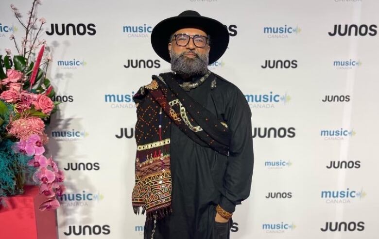 A man stands in traditional black South Asian attire on the Juno's red carpet. 