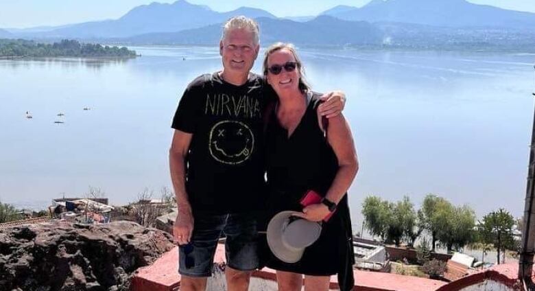 Sylvie Gadbois poses for a photo with her husband in front of landscape in Mexico.