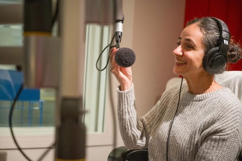 woman holds a mic and wear a head phone will looking away 