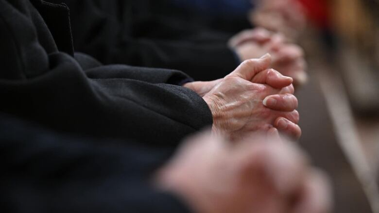 Priest folds hands in prayer