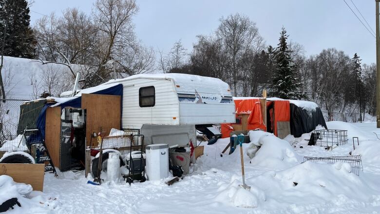 Two trailers being used as homes sit side by side in the snow.