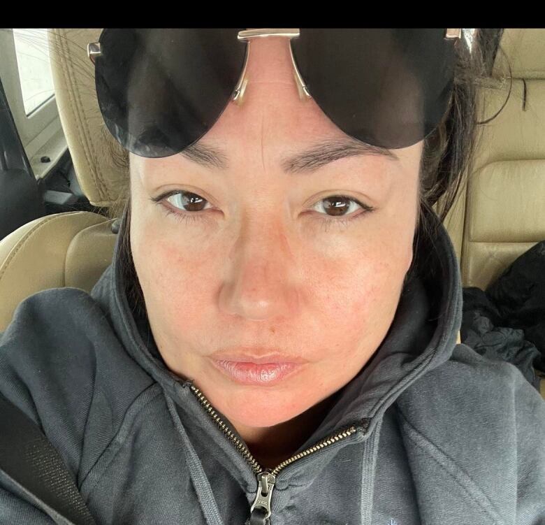 Woman with sunglasses sitting in the passenger seat of a vehicle.