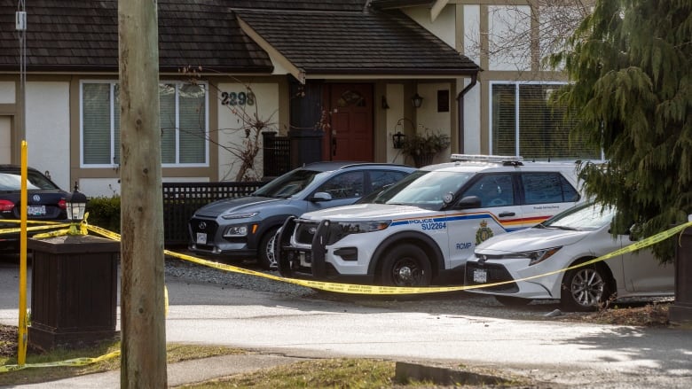 Yellow crime scene tape surrounded suburban homes.