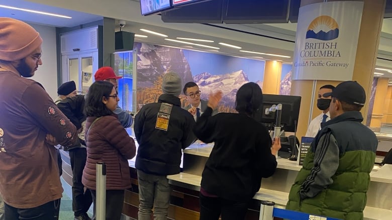 People stand at a desk talking to people on the other side of it