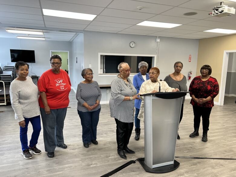 A group of women stand around a podium. 