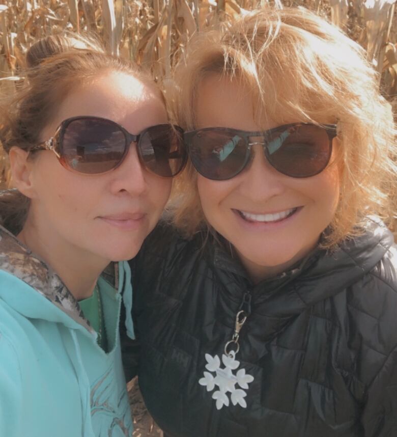 Two women, smiling in a field of tall white corn.