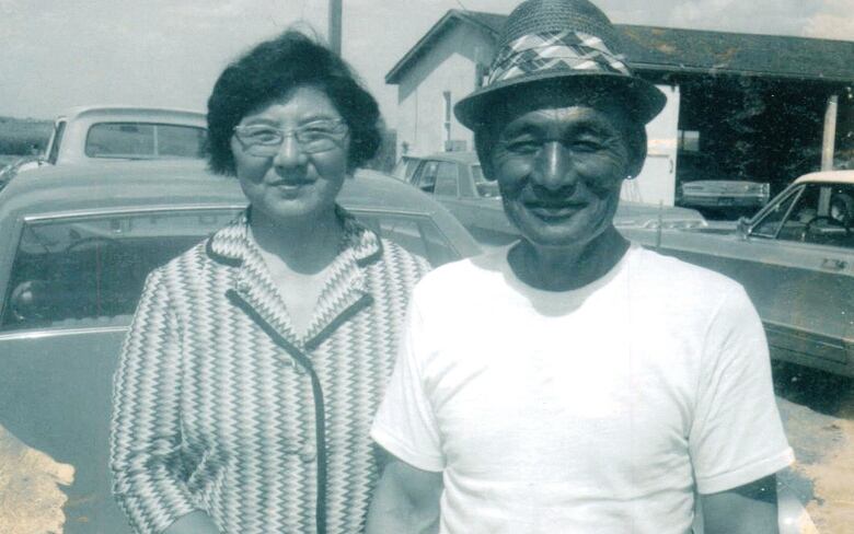 A man and woman stand next to each other in a black and white photo.