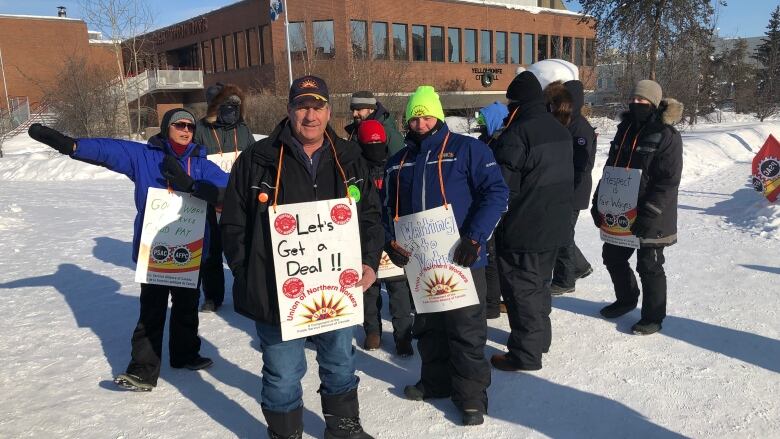 Picketing Yellowknife city workers pose in front of City Hall in winter.