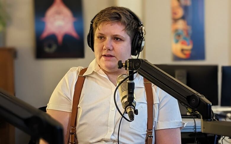 A woman sits at a microphone in a radio studio.