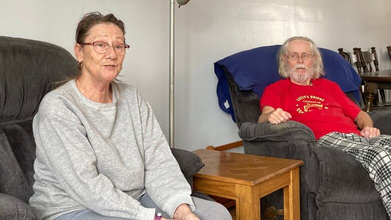 A an older woman and man sit in a living room talking.