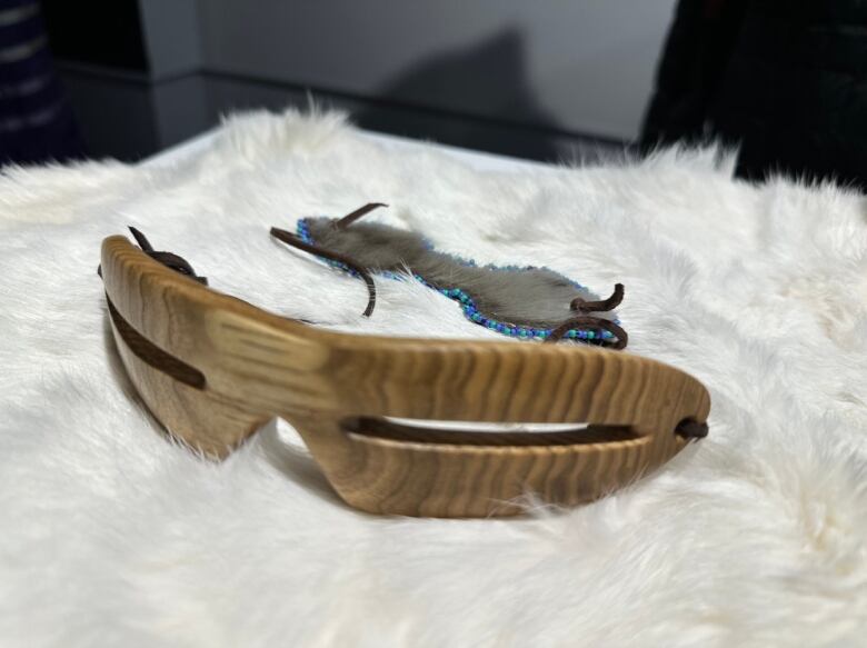 Eyewear carved from wood rests on white fabric.