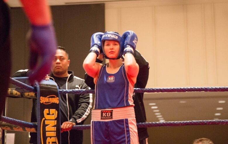 A boxer holds her head in the midst of a fight.