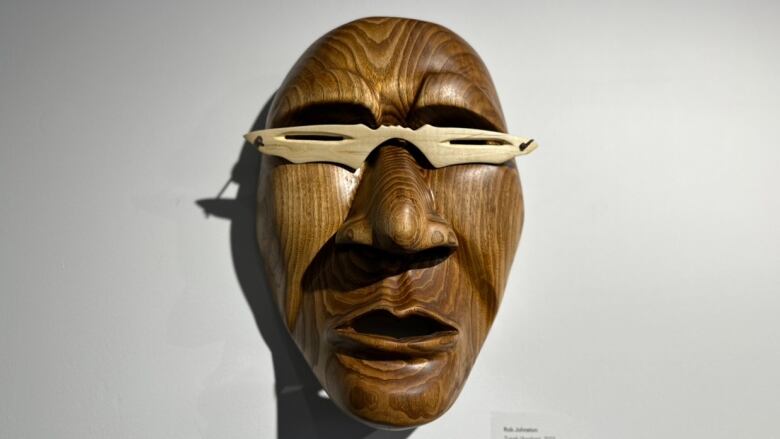 A wooden carving of a face hangs on the wall.