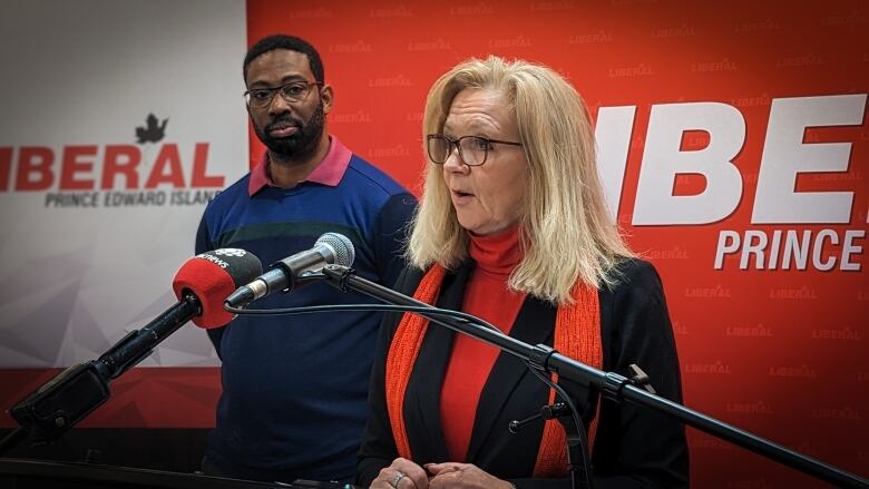 Liberal Leader Sharon Cameron stands at a podium with Liberal candidate Dellon Paul standing behind her. 