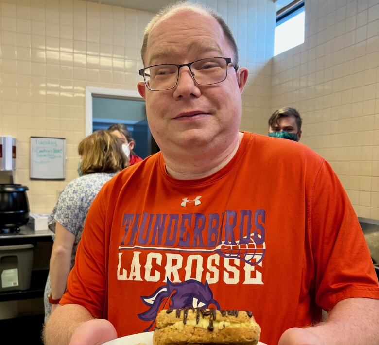 A man holds up baked goods for the camera