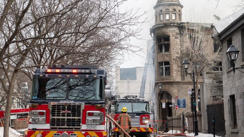 Firetrucks on a street in front of a charred building. 