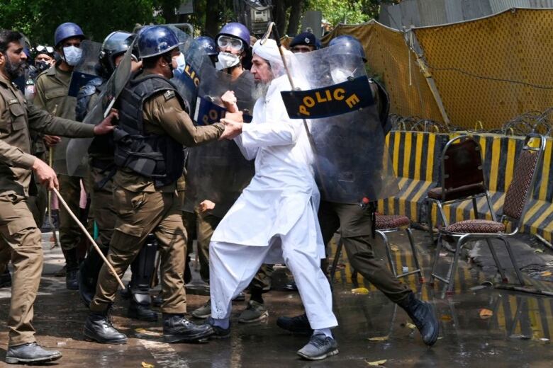 Riot police scuffle with a man near the home of Pakistan's former prime minister.