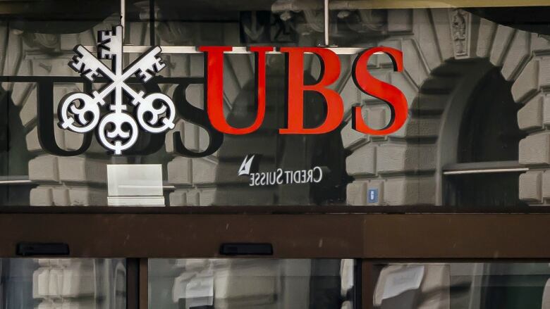 A UBS logo hangs in front of a window.