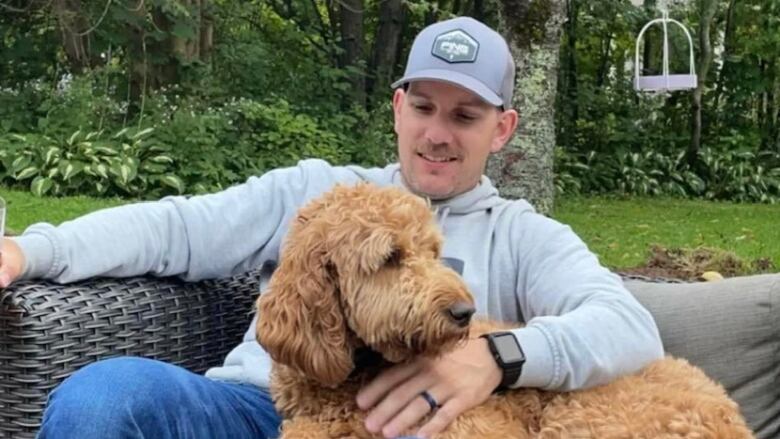 A man smiles as he holds his family dog. 