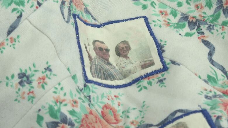 A patch of a quilt showing a white background and floral pattern with a photo of a man and a woman in the middle. 