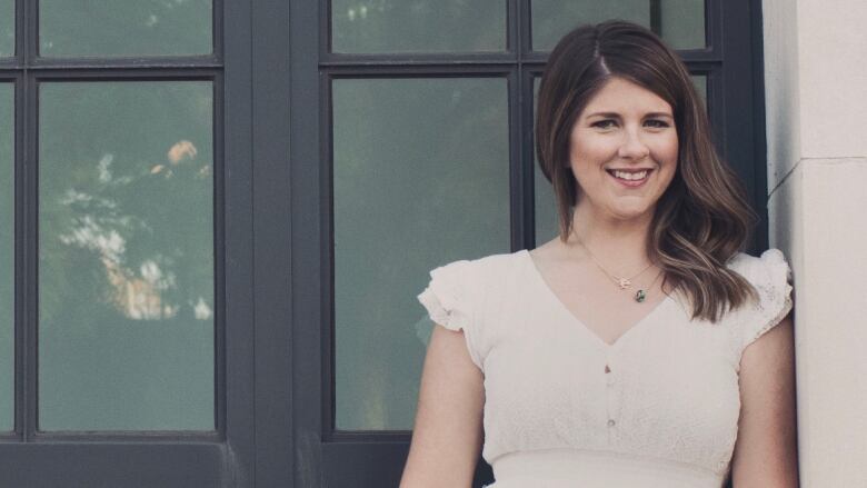 A woman in a white dress poses for a photo.