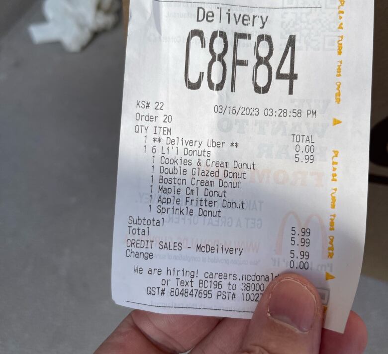 A person holds a McDonald's receipt in their hand. The receipt is for several donuts. 