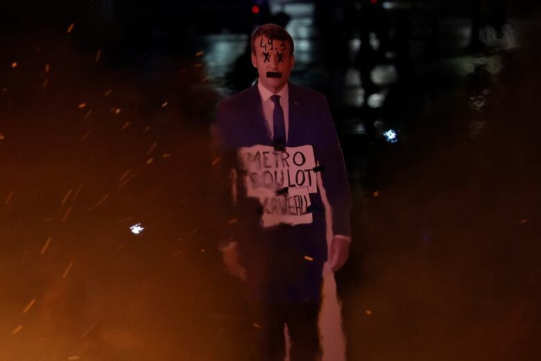 A defaced cardboard cutout of a politician in a suit is shown.