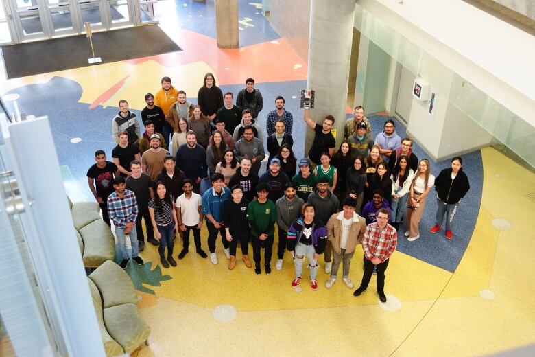 A drone shot of a group of students standing and looking up at the camera