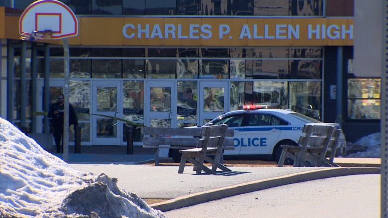 A police car is seen in front of a high school. 