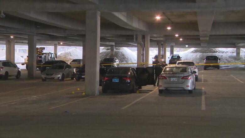 Police tape can be seen around a crime scene in an underground parking lot. 