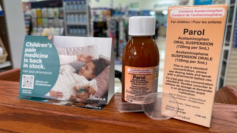 A medicine bottle, its box and a pamphlet on a wooden table.