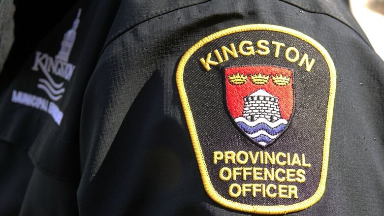 A closeup photo of a shoulder badge with the city of Kingston flag -- a tower with three crowns above it -- with the word Kingston in gold thread above it and the words provincial offences officer below.