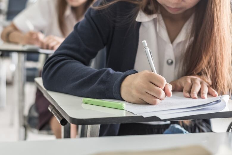 Student hand holding pen writing doing examination with blurred abstract background