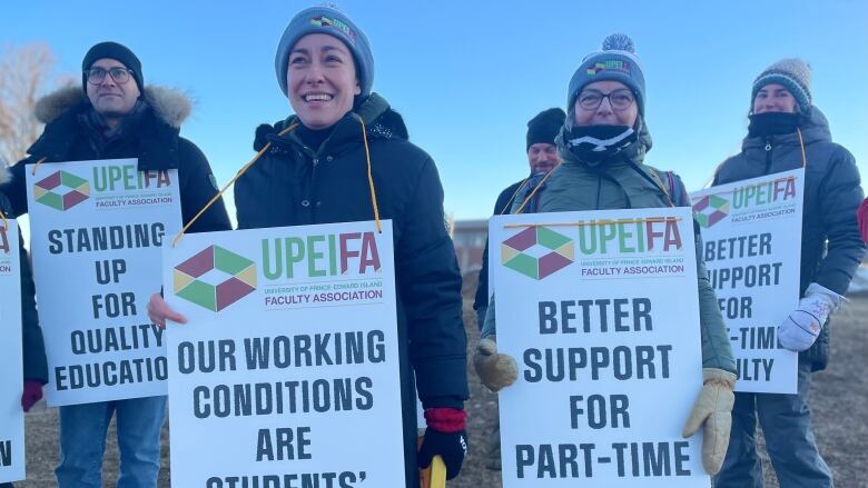 UPEI faculty members stand outside the main entrance to UPEI Monday, holding signs saying 'Better Support for Part-Time Faculty,