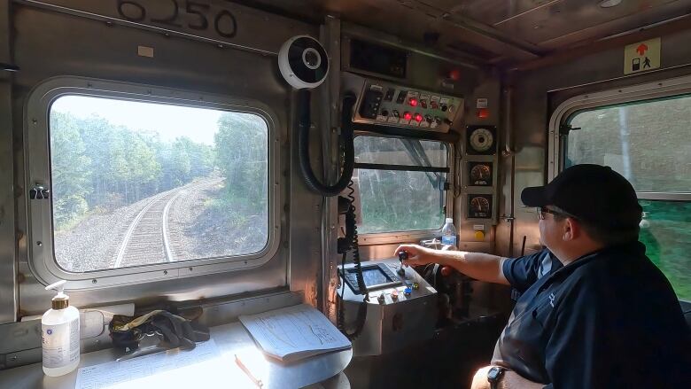 A locomotive engineer works at his controls at the front of a Budd RDC.