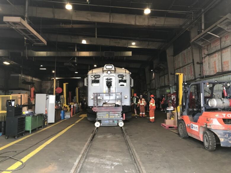 Workers standing with a railcar inside a covered workshop after a camera was put on the front of the train.