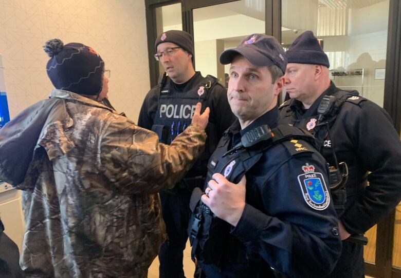 A man dressed in camouflage confronts three police officers. 