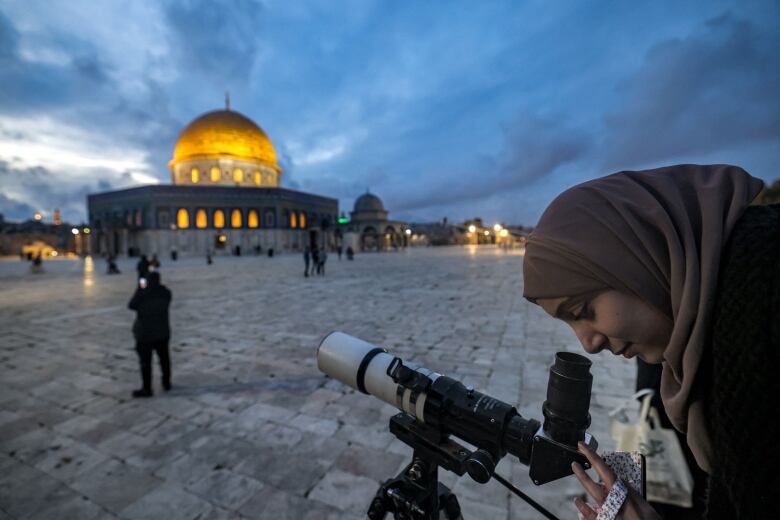 A woman looks into a telescope to check out the moon head of the start of Ramadan.