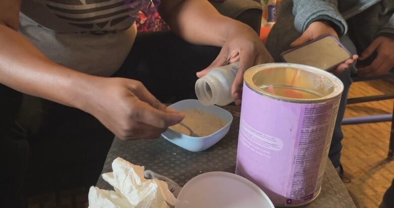 Someone mixes food from a can into a bowl.