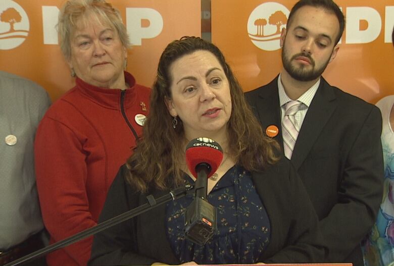 Michelle Neill at podium flanked by candidates.