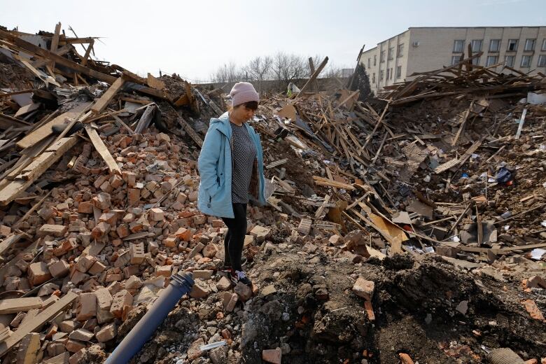 A woman stands near a shell crater in Donetsk, Ukraine.