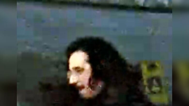 Blurry image of the head of a man with black hair an a moustache, seen from a side profile