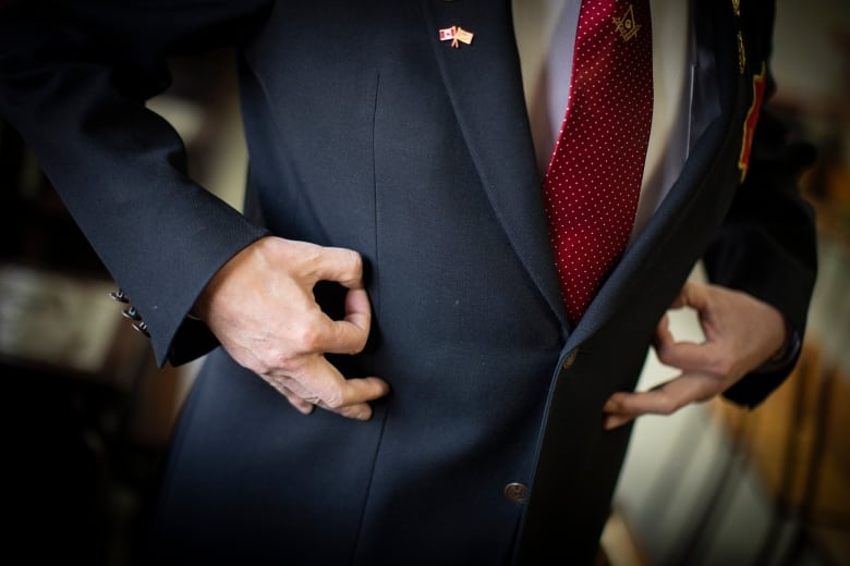 A man in a suit uses both his hands to do a signal