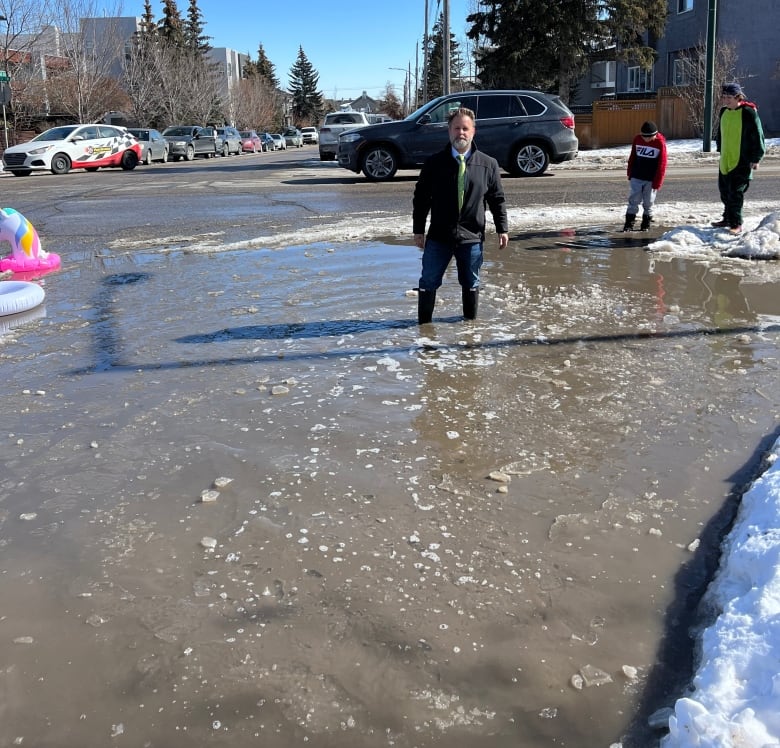 A man in rain boots stands in a pool of water.