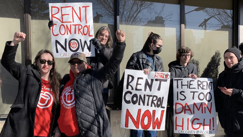 Five people holding signs protesting for rent control